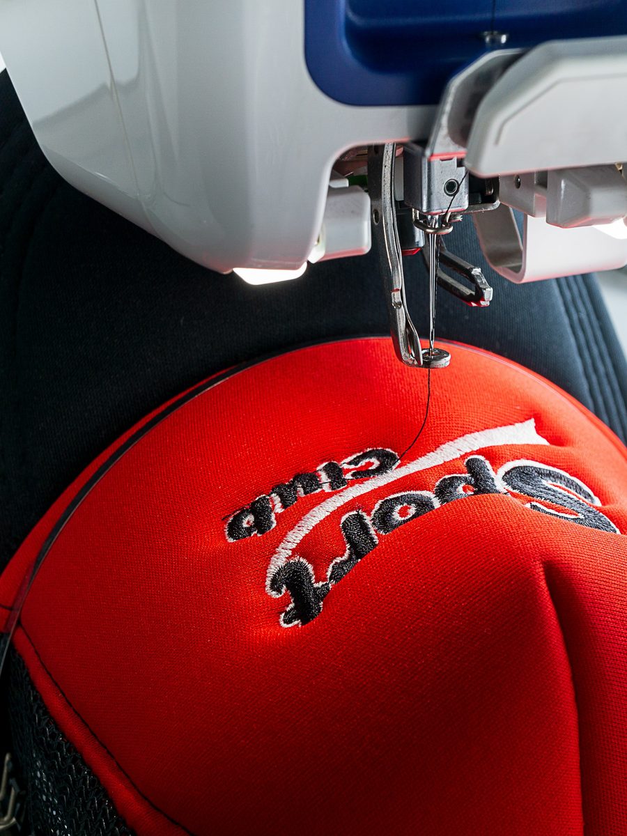 An embroidery machine stitching a logo onto a cap