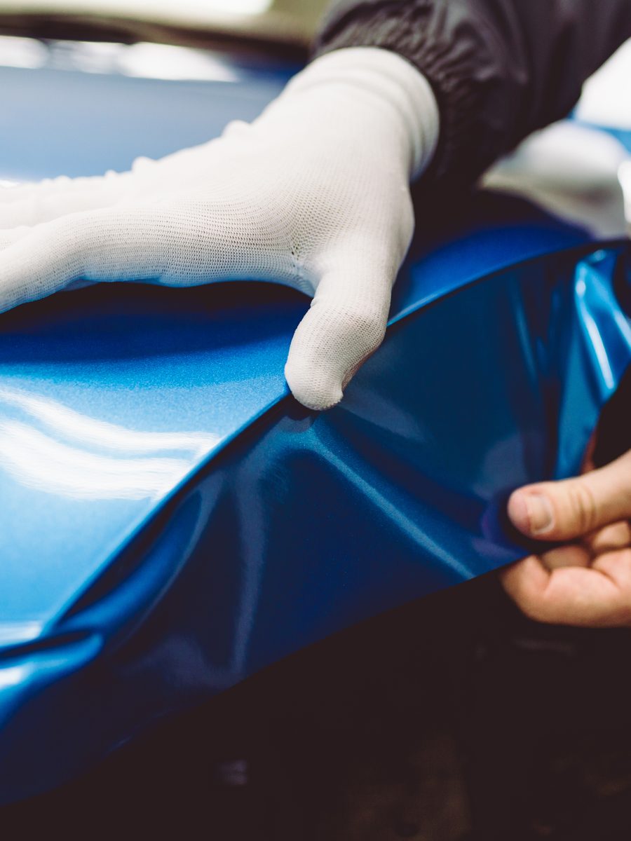 An installer smoothing vinyl wrap film onto a vehicle panel