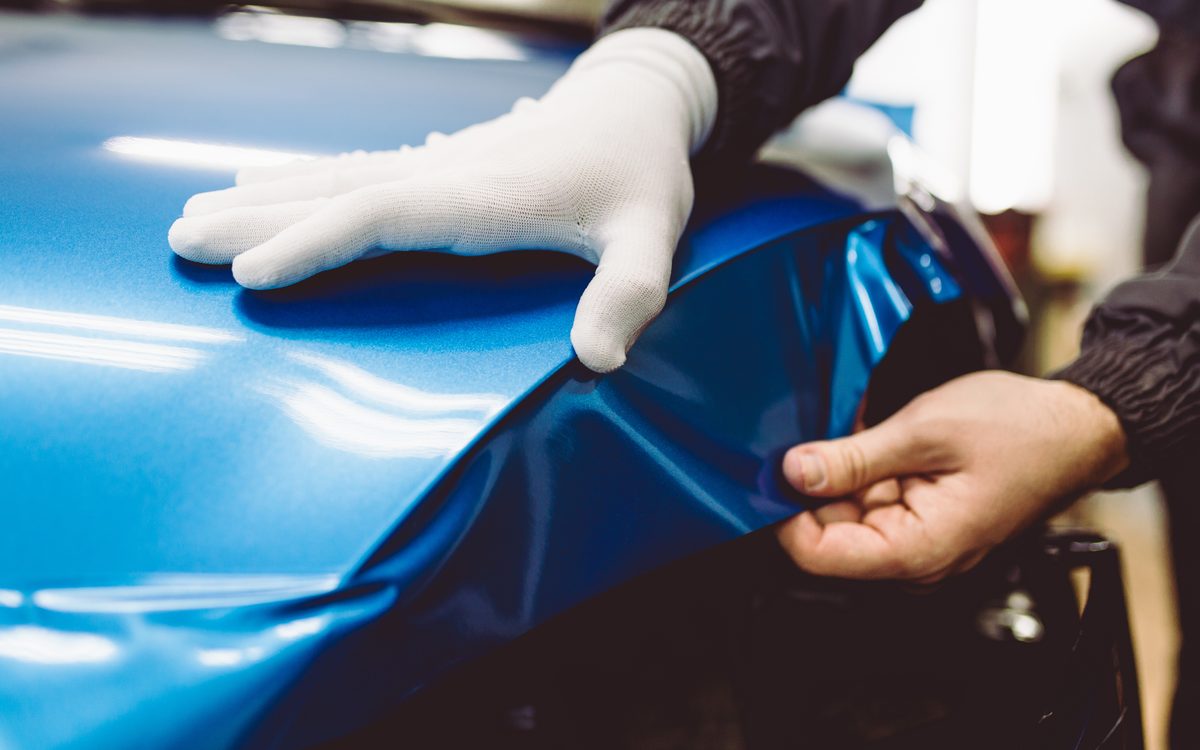 An installer smoothing vinyl wrap film onto a vehicle panel